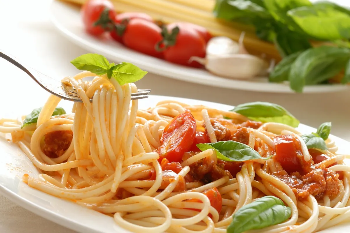 Espaguetis con tomate casero y hojas de albahaca fresca