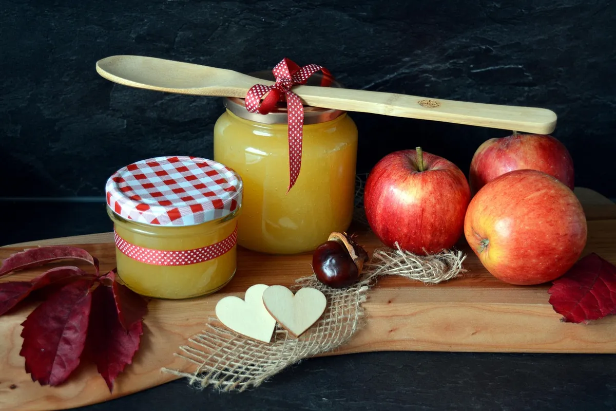 Compota de manzana casera en tarros junto a manzanas frescas