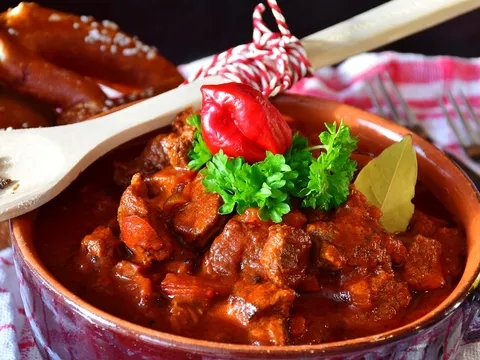 Carne en salsa de tomate y pimentón servida en un cuenco de barro