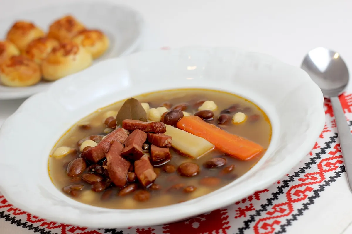 Alubias blancas guisadas con chorizo y verduras en un plato hondo