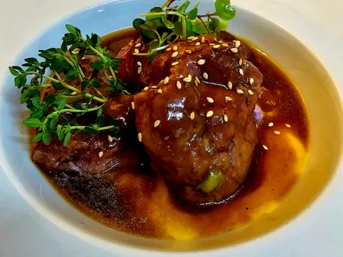 Carrilleras de cerdo en salsa servidas con la salsa de verduras y vino