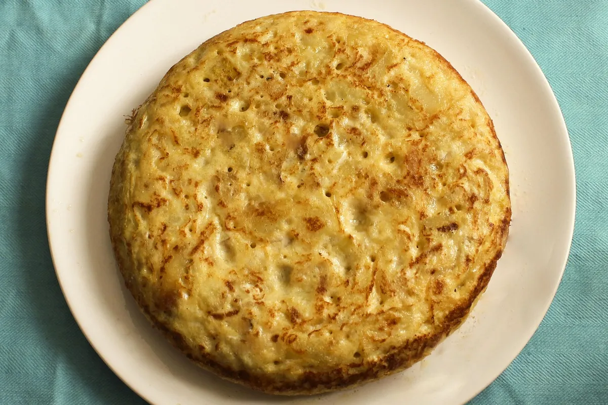 Tortilla de patatas con calabacín entera en un plato blanco