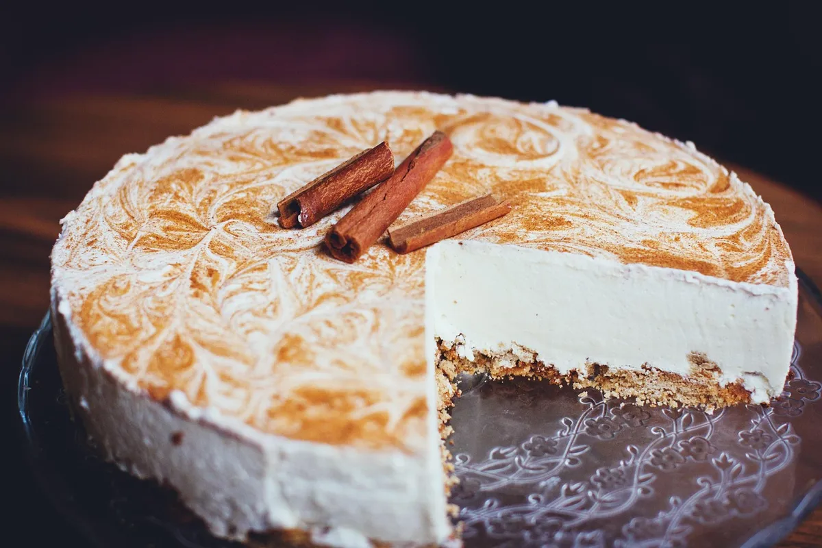 Tarta cremosa de queso con toque de canela, cortada mostrando el interior