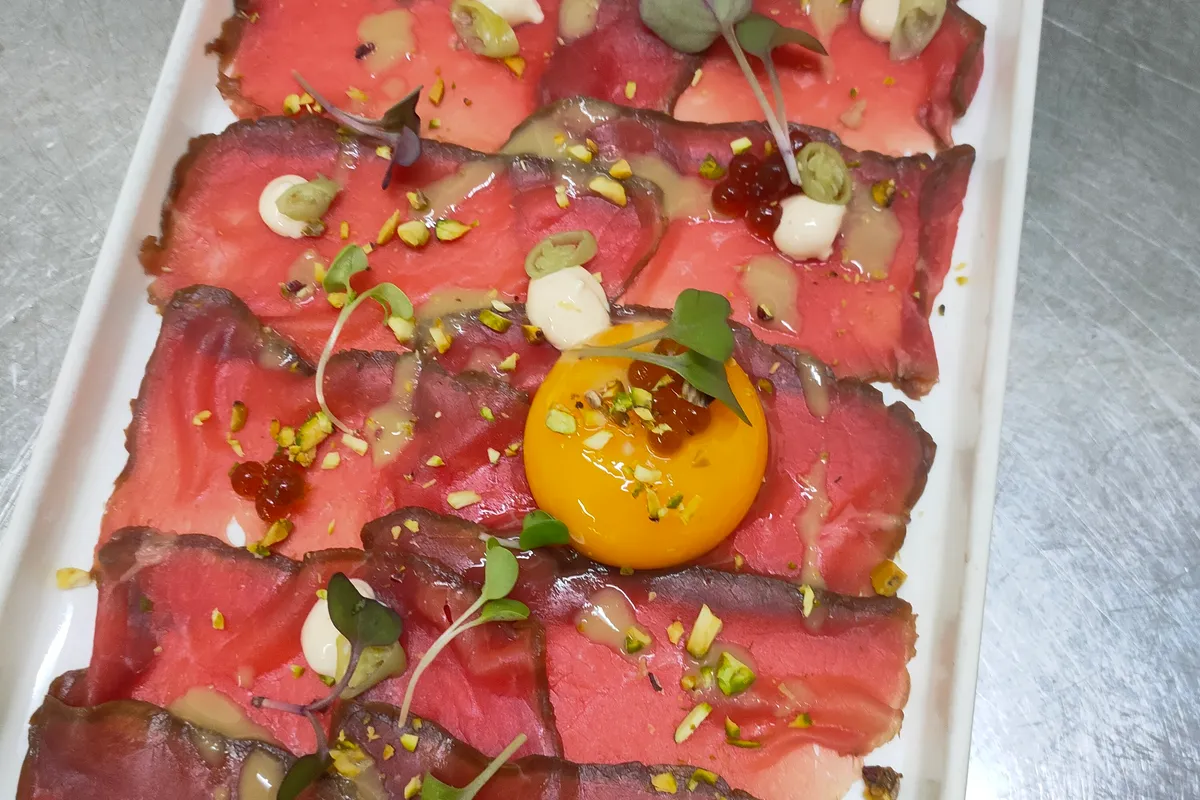 Carpaccio de wagyu en lonchas finas con pistacho picado y yema de huevo