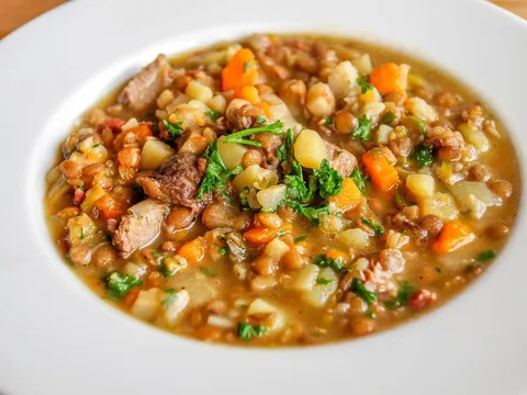 Lentejas guisadas con zanahoria, patata y carne servidas en un plato hondo