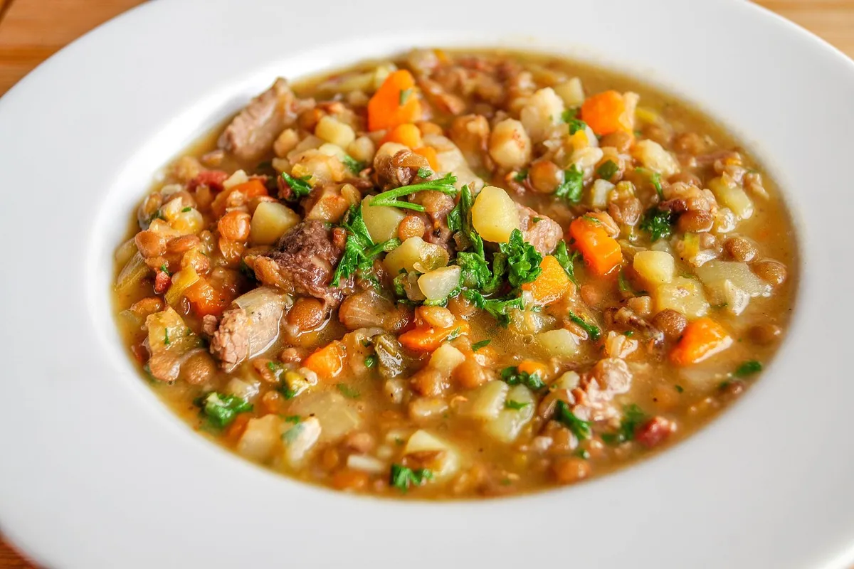 Lentejas guisadas con zanahoria, patata y carne servidas en un plato hondo